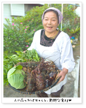 画像：「ふじ荘」のおばちゃん。抱えているザルの中には、新鮮な野菜と海の幸。